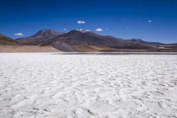 Another Salar - Un autre Salar Salt flats landscape in San Pedro de Atacama, with mountains under a clear blue sky.
