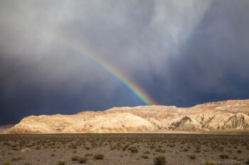 Altiplano Rainbow over desert landscape in San Pedro de Atacama, with dramatic clouds and colorful mountains.