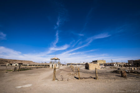 Oficina Humberstone (UNESCO) Desert scene in Fiambala, Argentina with clear blue sky and rustic structures, captured by Olivier S.