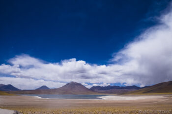 Laguna Miñiques San Pedro de Atacama desert with mountains and dramatic sky.