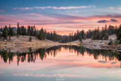 A peaceful mountain lake scene captured during sunset, showcasing vibrant sky colors and tranquil water reflections. Serene mountain lake at sunset with colorful sky and calm waters reflecting the landscape.