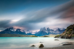 Scenic mountain lake scene featuring tranquil waters, rugged peaks, and dramatic sky, perfect for nature photography. Beautiful mountain lake with calm waters and snow-capped peaks in the background.