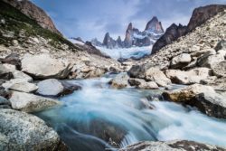 Stunning mountain scenery with a glacier, rocky peaks, and a rushing river, showcasing the beauty of nature. Majestic mountain landscape featuring a glacier, rugged peaks, and a flowing river in the foreground.