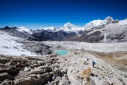 Stunning mountain scenery featuring snow-covered peaks, a glacier lake, and hikers exploring the rugged terrain. Snowy mountain landscape with glacier lake and hikers in the foreground.