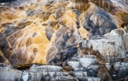 Stunning geological formations captured by Olivier Steiner, showcasing vibrant colors and intricate textures. Golden mountain landscape with colorful rock formations and textured surfaces.