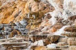 Stunning geothermal landscape with mineral terraces and waterfalls, showcasing vibrant natural colors and formations. Waterfalls cascading over colorful mineral terraces in a geothermal area.