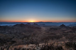 A breathtaking view of a mountain range at sunrise, showcasing the natural beauty and serenity of the landscape. Sunset over rugged mountain landscape with vibrant sky and rolling hills.