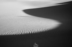 Minimalist black and white sand dunes with textured patterns and shadows. Sand dunes in black and white, abstract landscape photography.