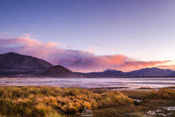 A peaceful mountain lake scene captured at sunset, showcasing vibrant colors and tranquil waters. Serene mountain lake landscape during sunset with colorful sky and surrounding mountains.