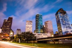 A stunning view of Houston's downtown skyline during sunset, showcasing modern skyscrapers and city lights. Houston city skyline at dusk with tall, illuminated skyscrapers and vibrant city lights.