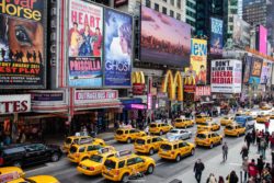 Vibrant scene of yellow taxis and bright billboards in Times Square, capturing the lively urban atmosphere. Yellow taxis in Times Square, NYC with billboards and pedestrians.