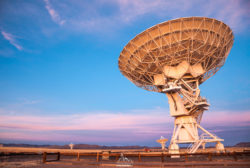 A large radio telescope dish captures signals from space under a vibrant sunset sky. Perfect for astrophotography and science enthusiasts. Radio telescope dish against colorful sunset sky.
