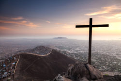 A scenic sunset scene featuring a large cross on a mountain peak overlooking Rio de Janeiro, capturing the peaceful and spiritual atmosphere of the lo. Sunset view with a cross on a mountain overlooking Rio de Janeiro at dusk.
