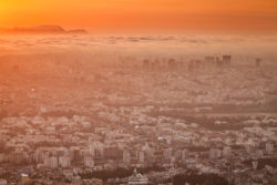 A stunning aerial view of Los Angeles during sunset, showcasing the city's skyline, mountains, and vibrant sky. Los Angeles city skyline at sunset with warm orange hues and sprawling urban landscape.