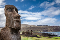 Iconic Moai statue on Easter Island overlooking the ocean, capturing the island's mysterious history. Moai statue on Easter Island with scenic ocean and sky backdrop.